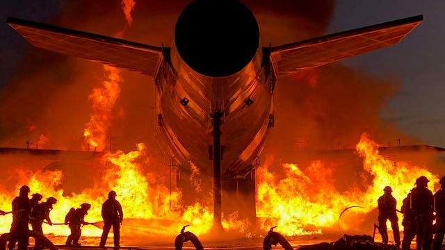 Firefighters fighting a fire near a burning airplane.