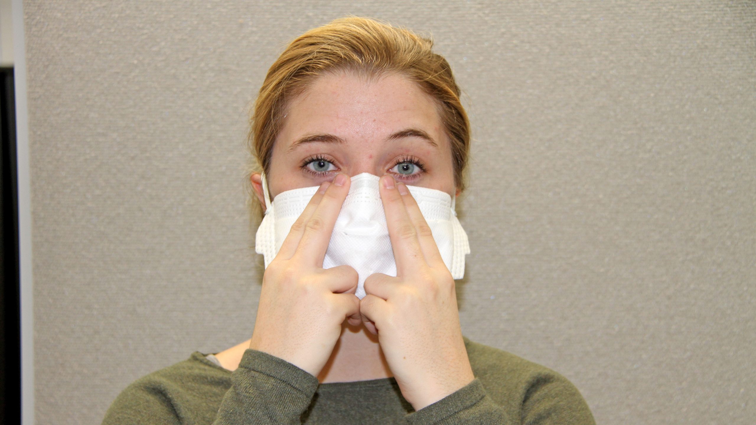 Respirator user performing a negative pressure user seal check on an FFR with their hands placed gently over the FFR.