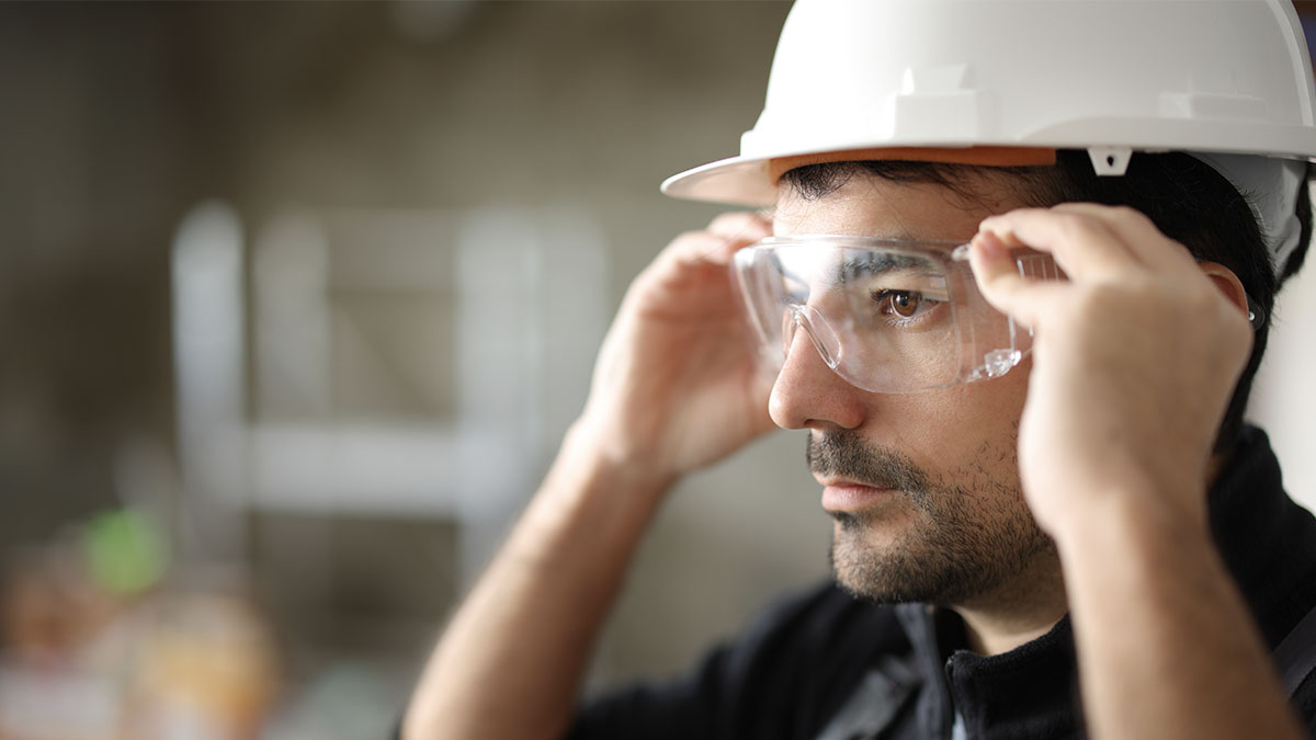 Construction working wearing clear protective eyewear and checking fit.