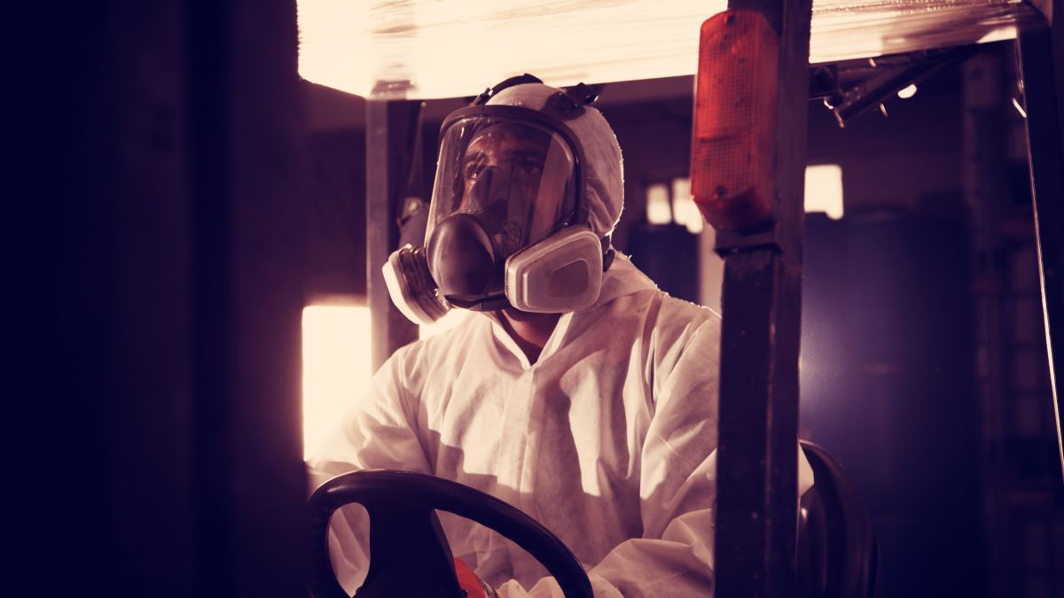 Worker gazing upward while operating a forklift wearing an elastomeric full facepiece respirator