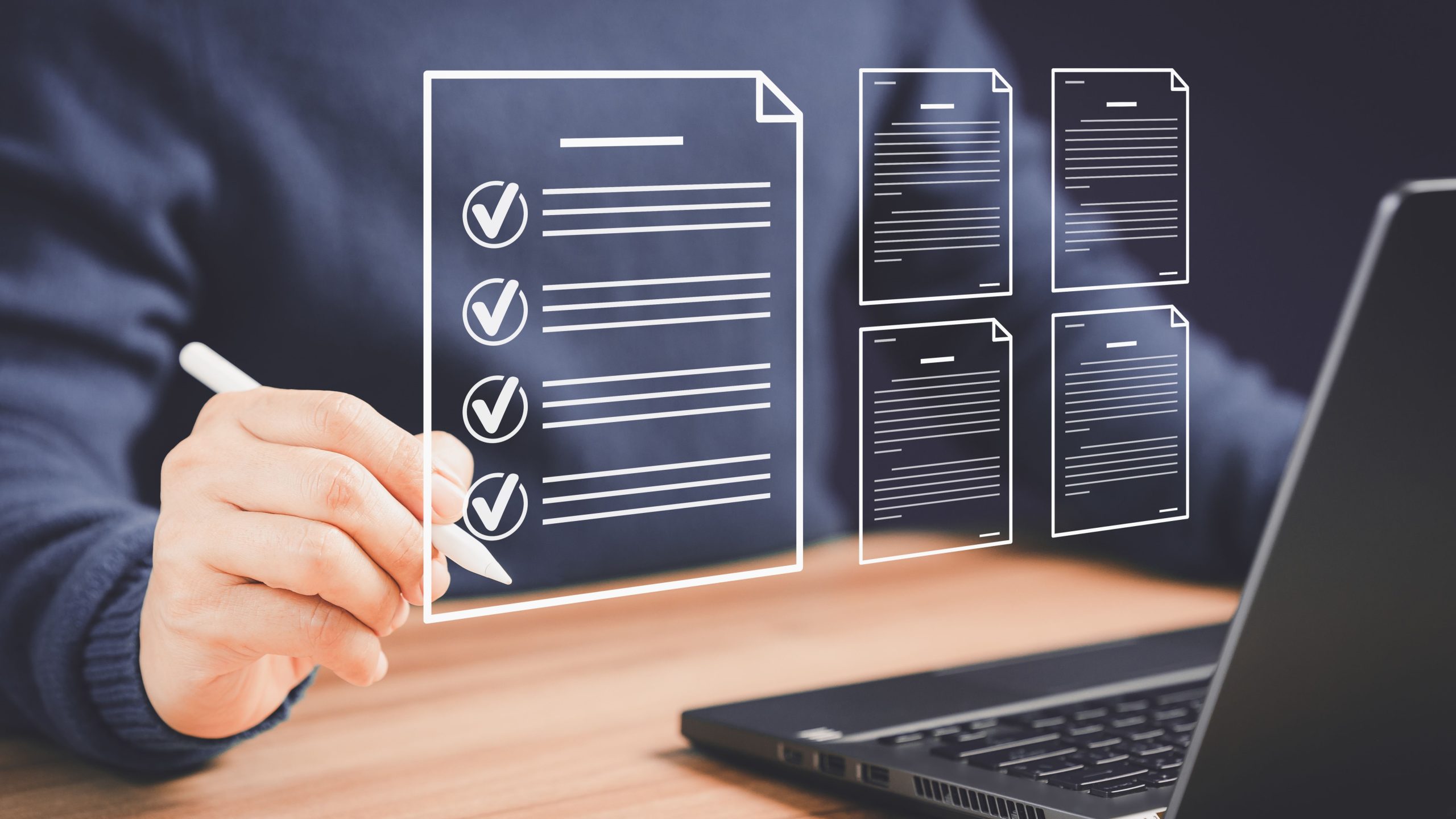 Individual at computer with graphics of documents in front of them. Checking boxes on one of the documents.
