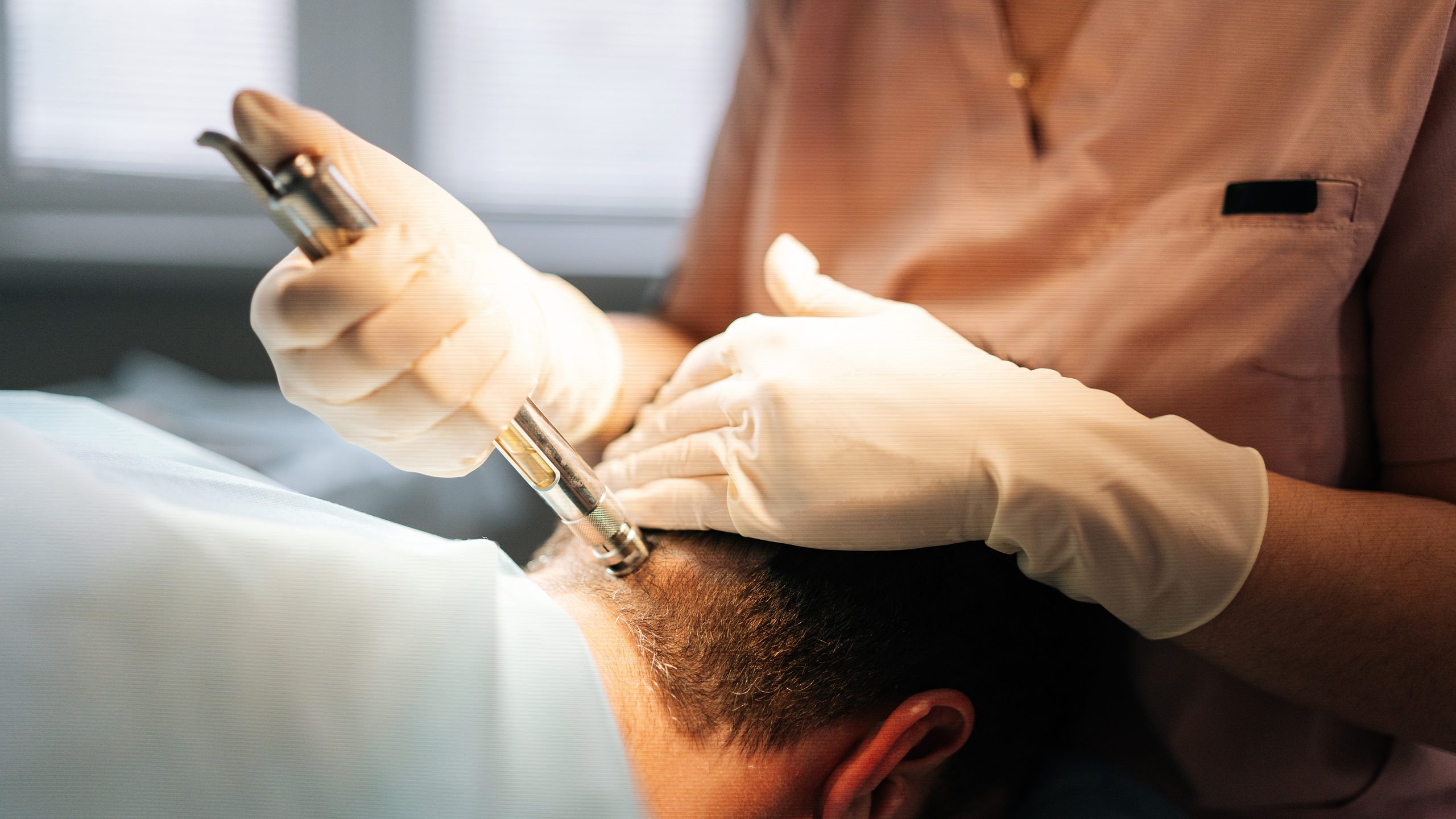 Close-up of a female anesthesiologist performing local sharps-free anesthesia to the back of a patient's head.