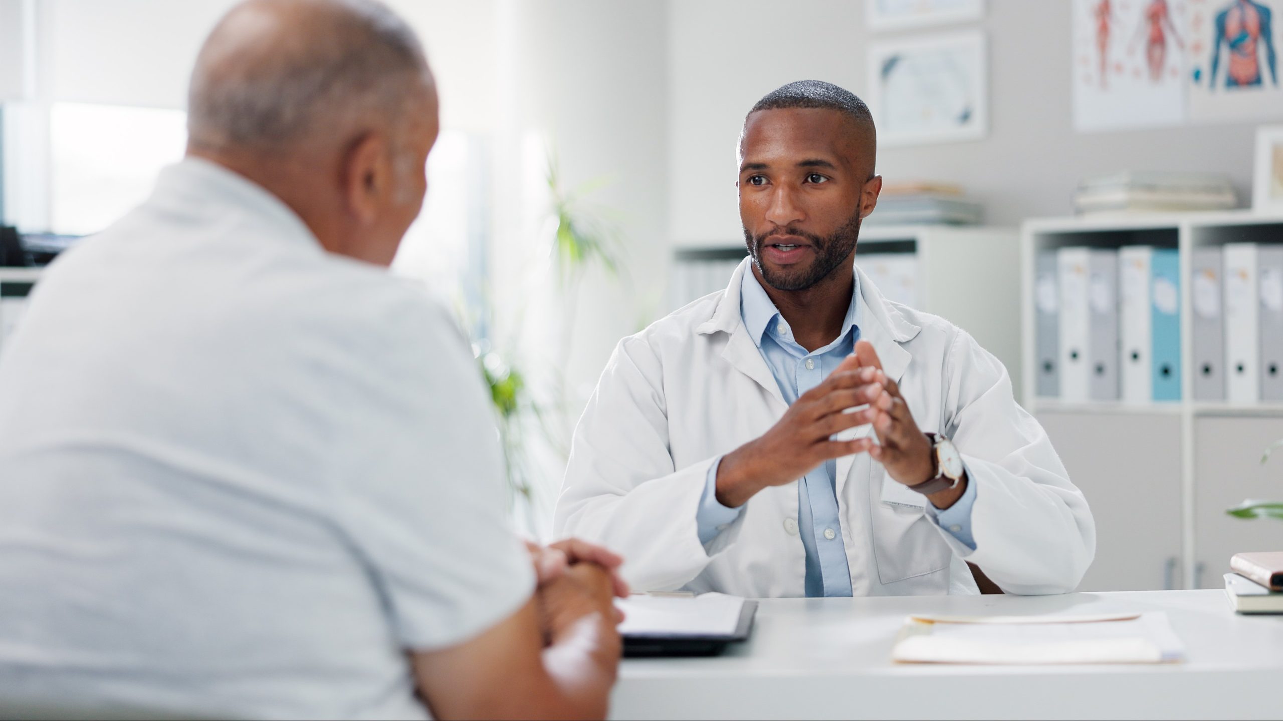 A man sitting at a desk meeting with a male doctor.