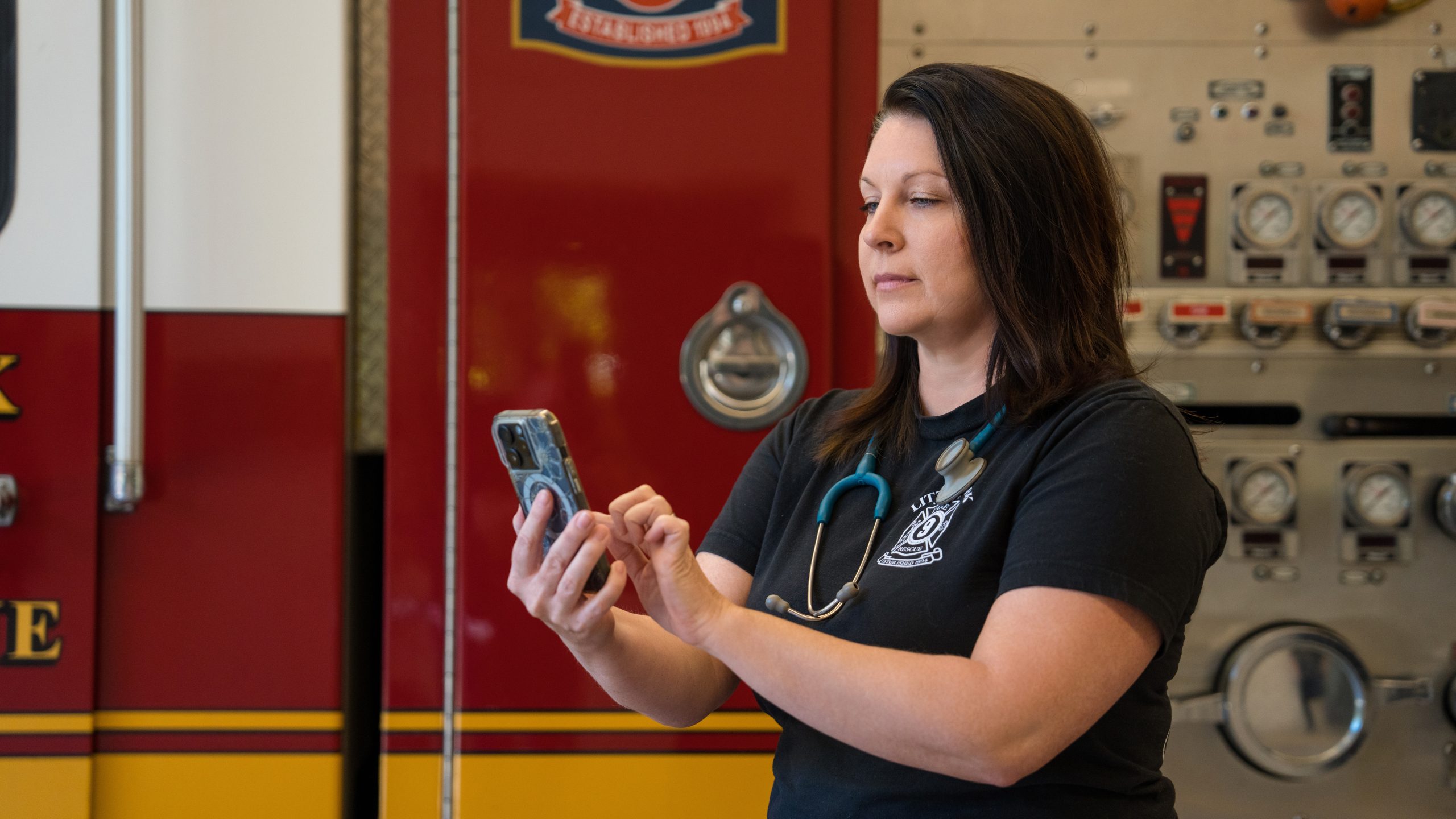Female Firefighter on smart phone in front of fire truck
