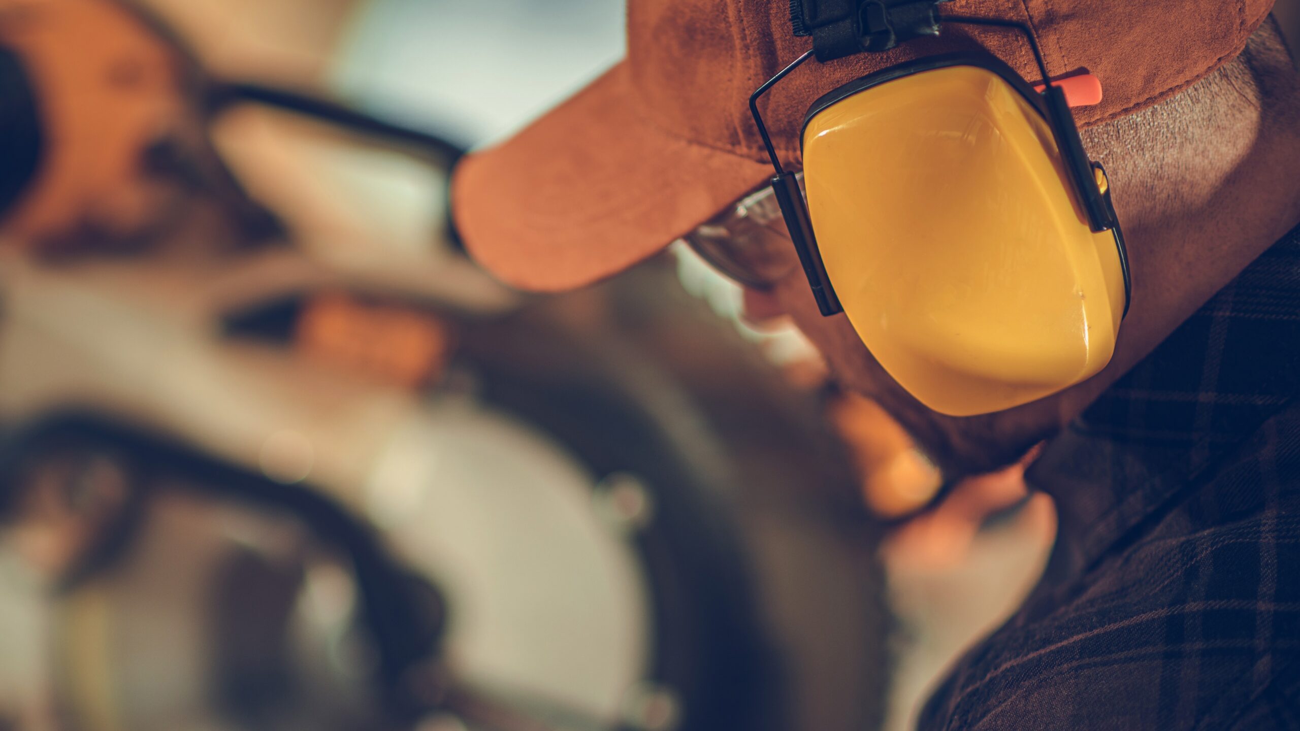 Man on a construction site wearing hearing protection in the form of safety earmuffs
