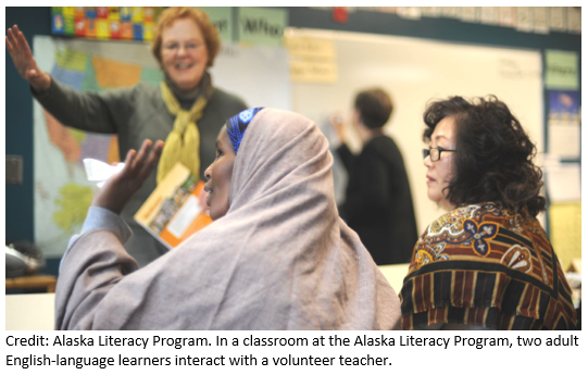 Two adult English-language learners interact with a volunteer teacher in a classroom at the Alaska Literacy Program.