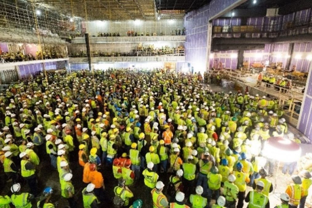 Large group of construction workers at worksite gather to listen to fall prevention presentation