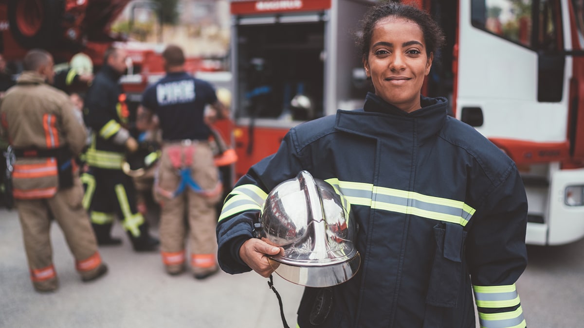 Pregnant female firefighter in foreground, with other firefighters in the background.