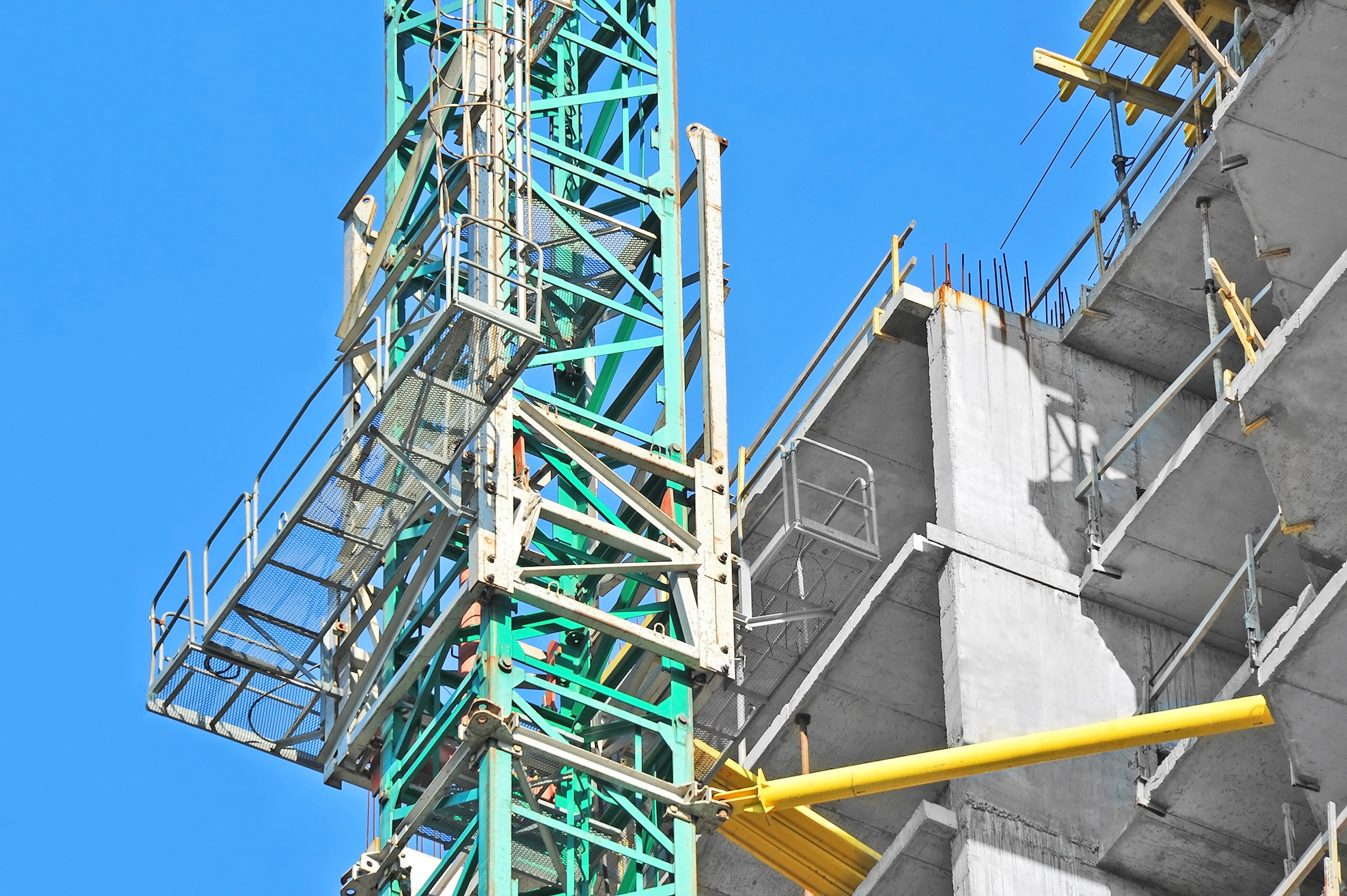 Mast climbing work platform is next to a building under construction.