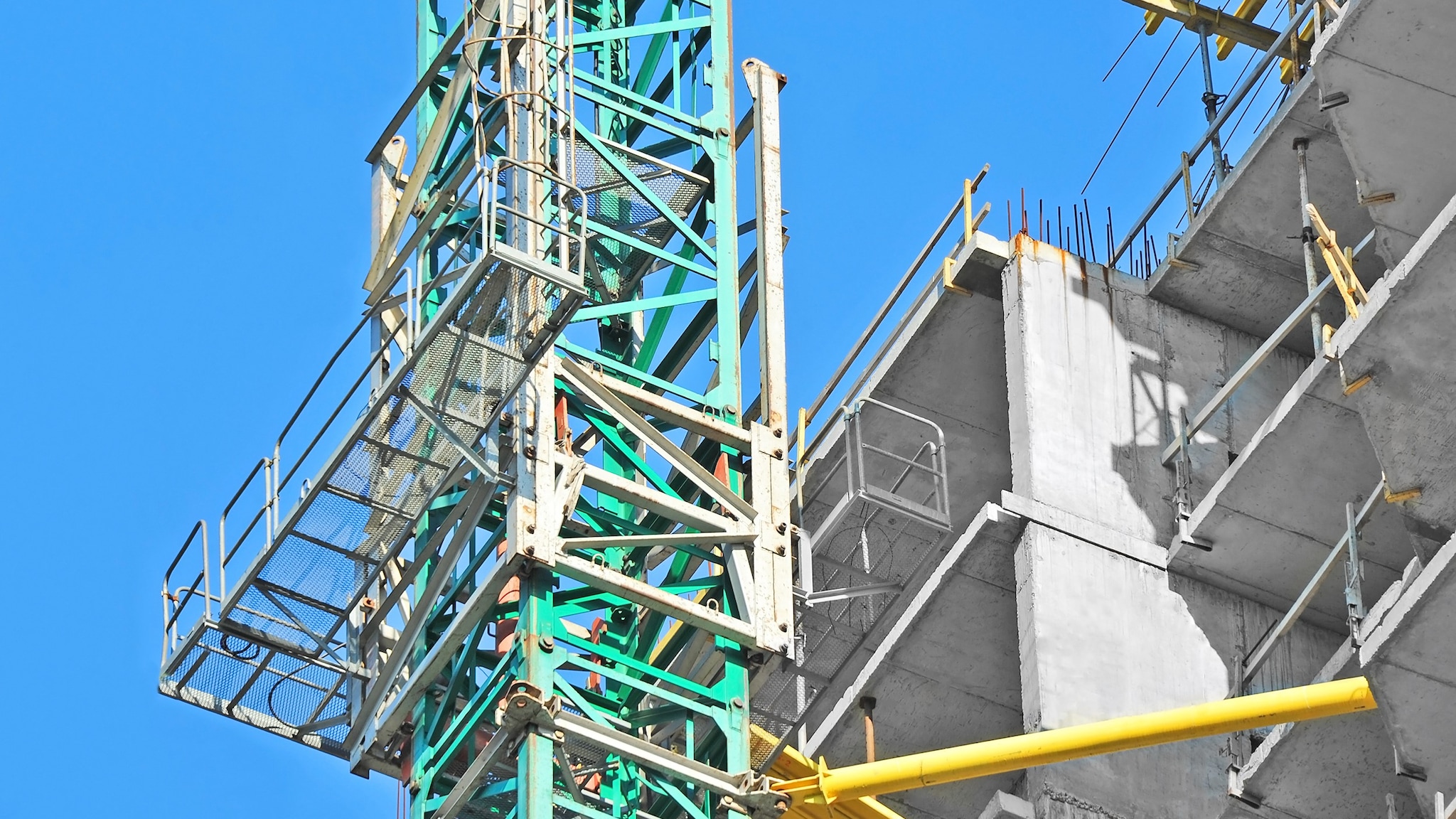 Mast climbing work platform is next to a building under construction.