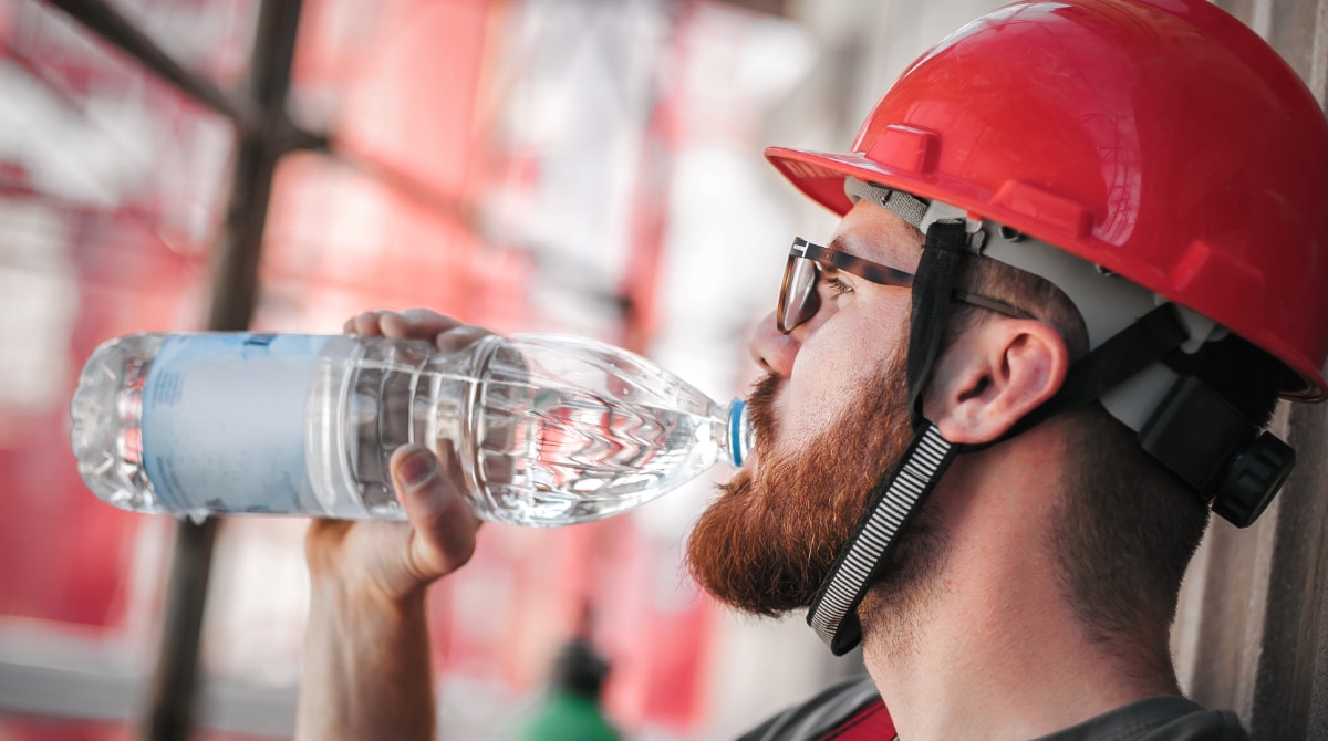 Worker in hard hat, sitting and drinking big bottle of water