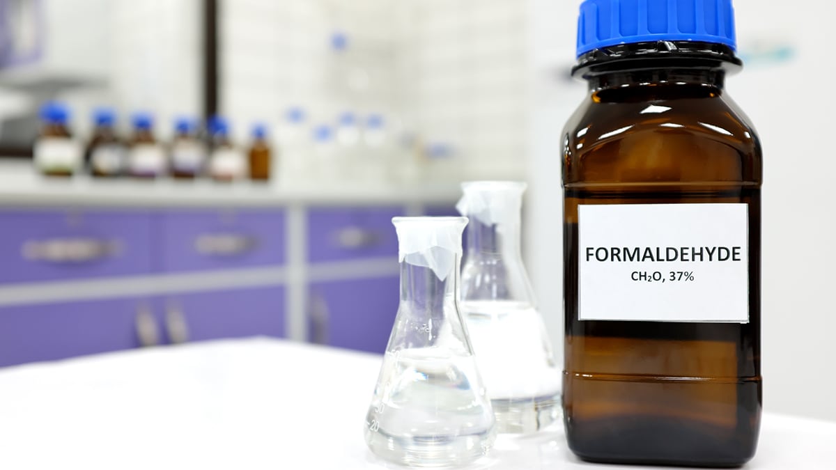 A bottle of formaldehyde shown in the foreground of a laboratory setting.