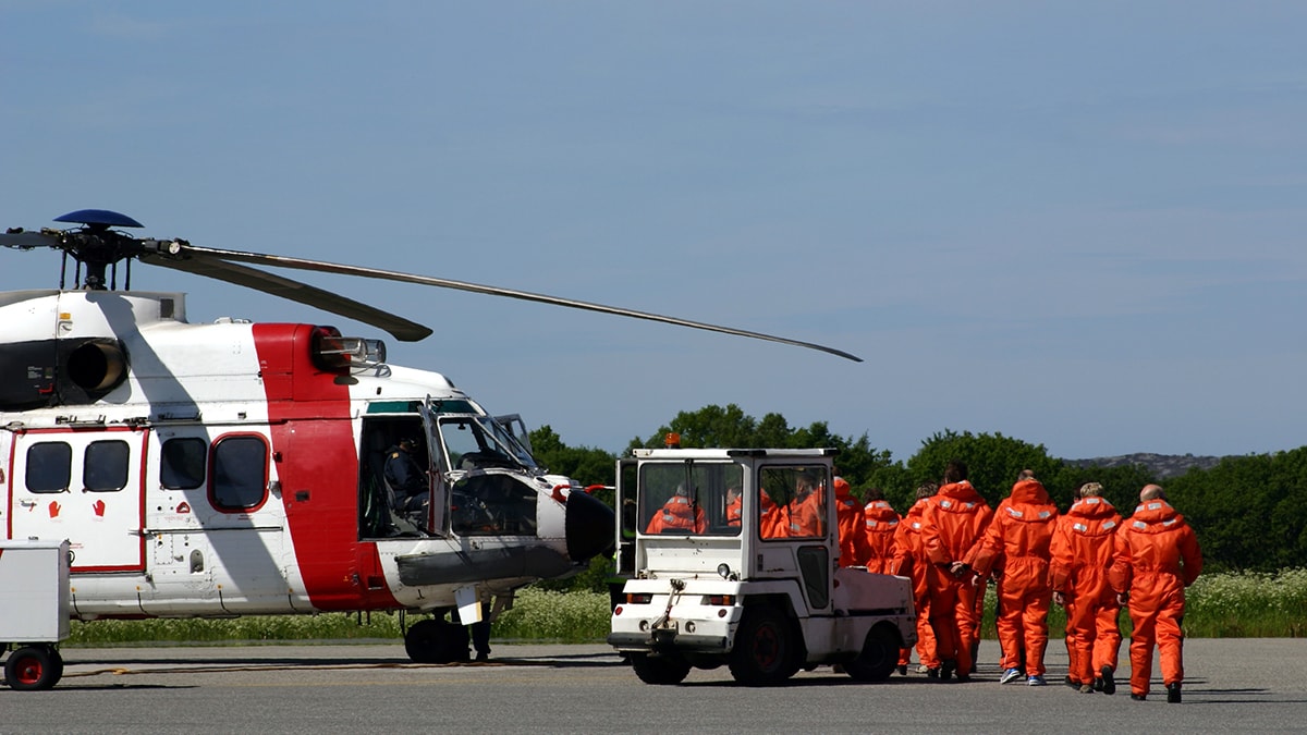 workers in orange uniforms walking next to a helicopter