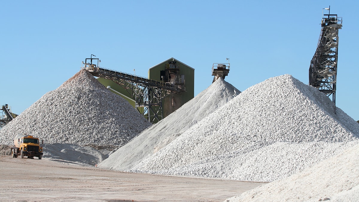 Surface mine with piles of gravel and heavy equipment.