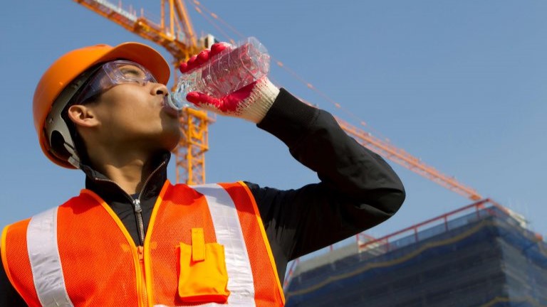 Construction worker in safety gear drinking water
