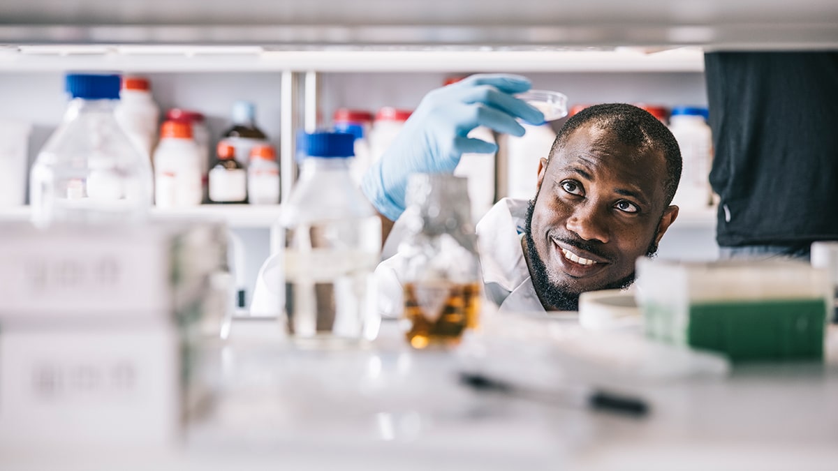 Laboratory scientist looking into petri dish, surrounded by lab supplies