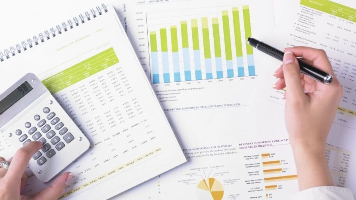 Hands over printed graphs and tables, using a calculator.