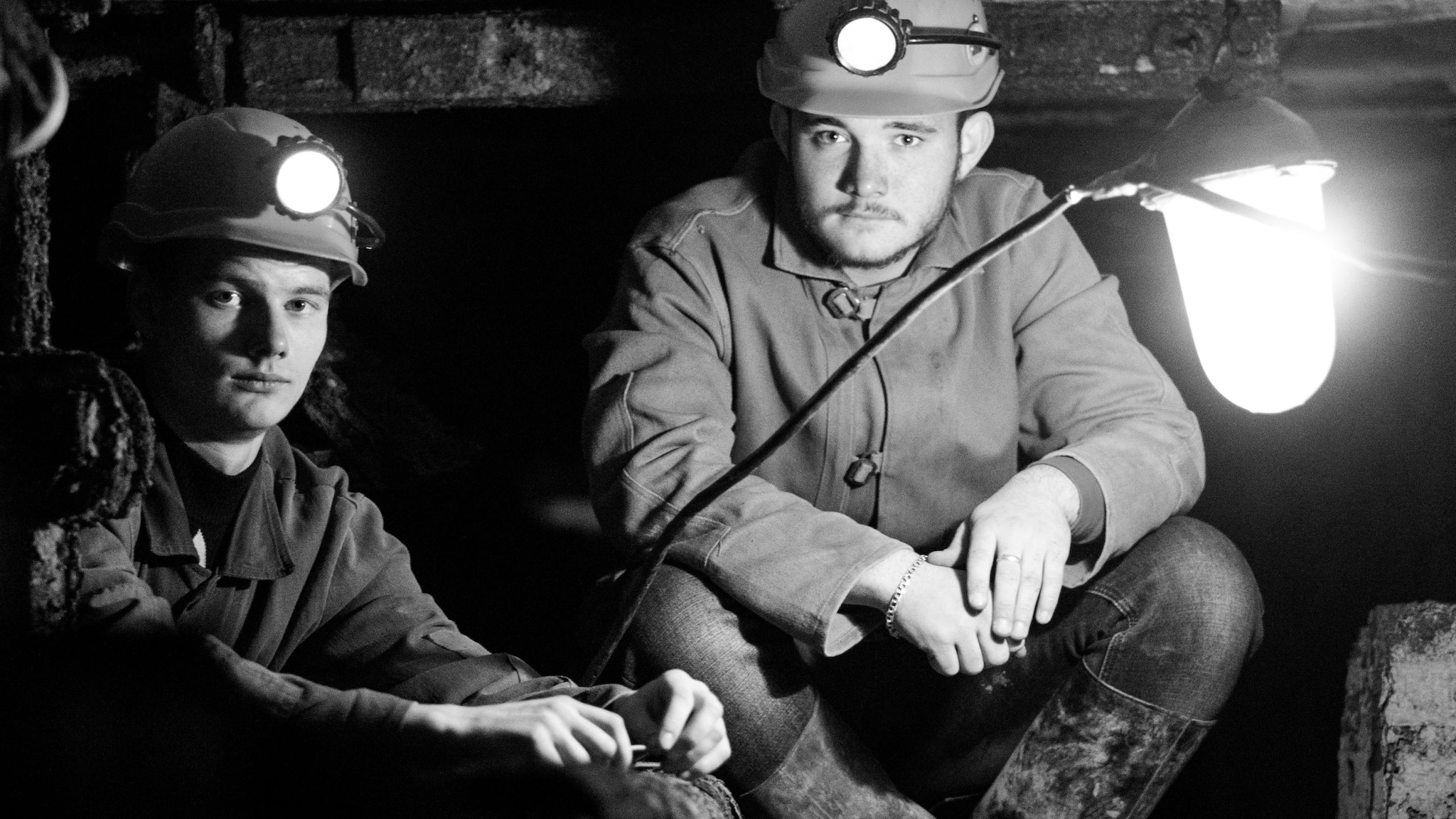 Two coal miners sitting in underground mine.