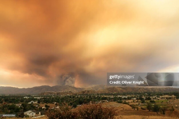 Heavy orange smoke clouds darken the sky from a wildland fire.