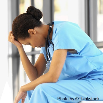 skd238146sdc A nurse sits with her hand on her forehead