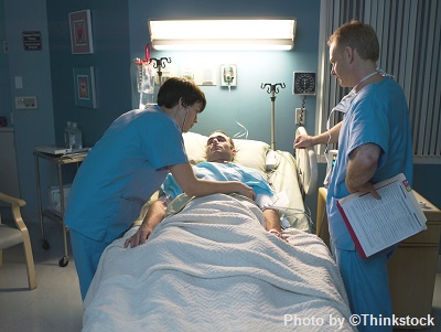 --no title-- Two medical staff in a hospital room attend a patient in bed
