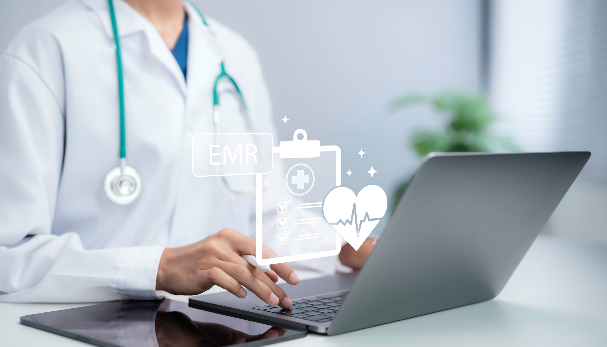 Doctor typing on laptop reviewing electronic medical records