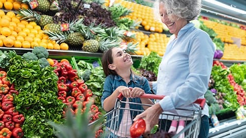 Grandmother and child shopping for fruits and vegetables in grocery.