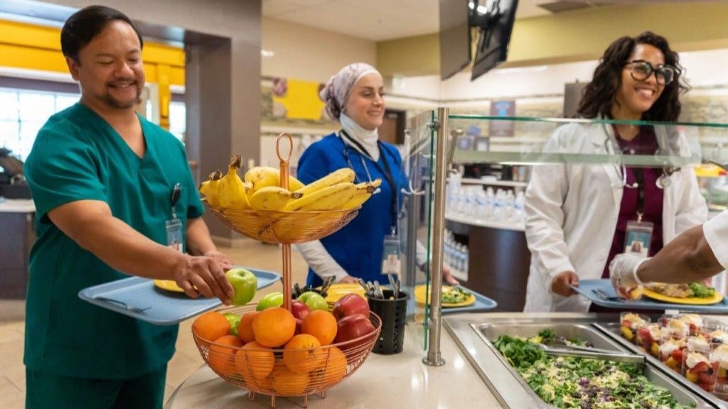 Medical staff choosing healthy options in serving line of hospital cafeteria.