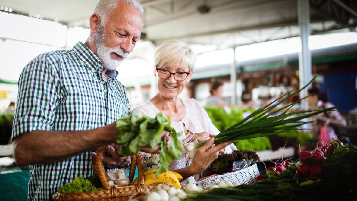 Elderly man and woman shopping at farmers' market.