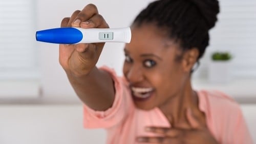 Woman looks happy with result of an at-home pregnancy test.