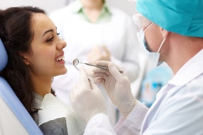 A smiling patient getting her teeth worked on by dentist