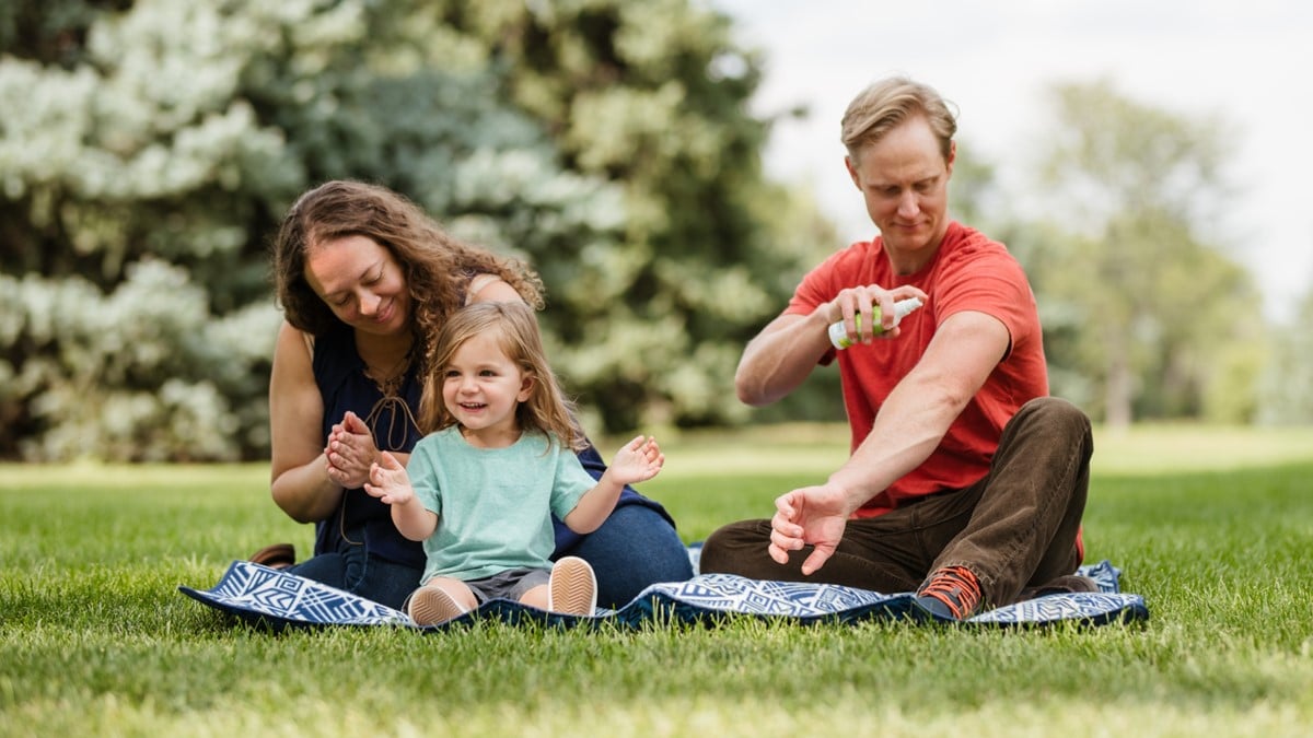 Family on a picnic and using insect repellent to protect themselves from bug bites.