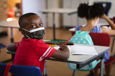 child-mask Boy wearing face mask at desk in elementary school
