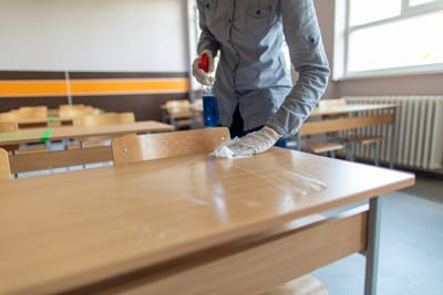 Teacher disinfecting school desk