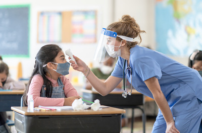 nurse-ppe School nurse wearing PPE taking student's temperature