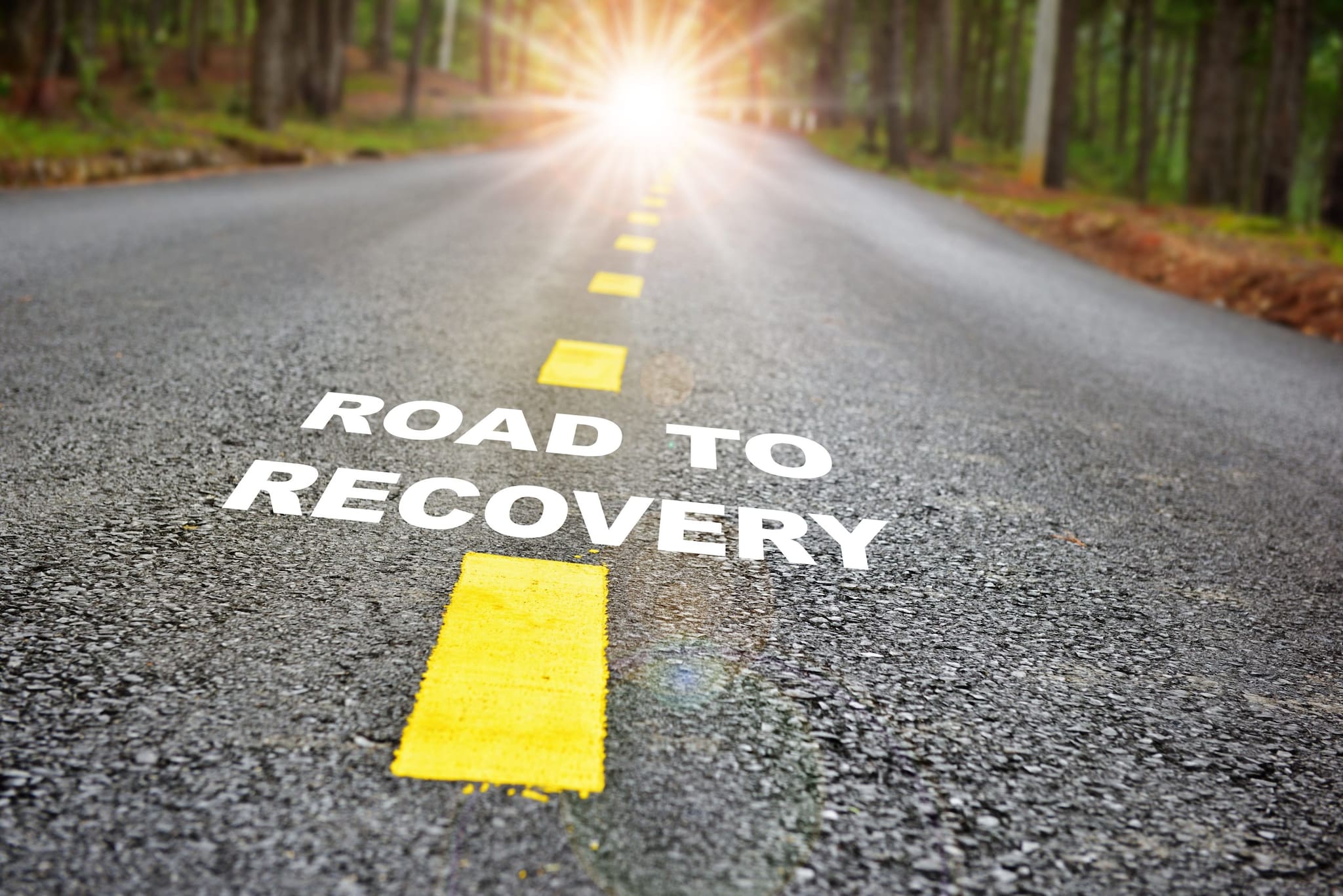 Road with dotted yellow line down the middle and the words "Road to recovery" written across.