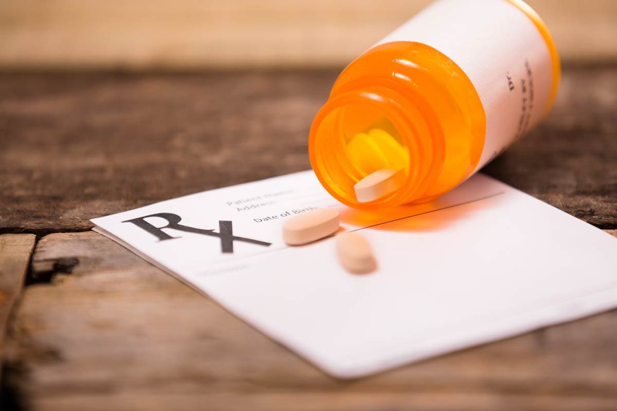 Antiviral pills spilling out of bottle over prescription pad