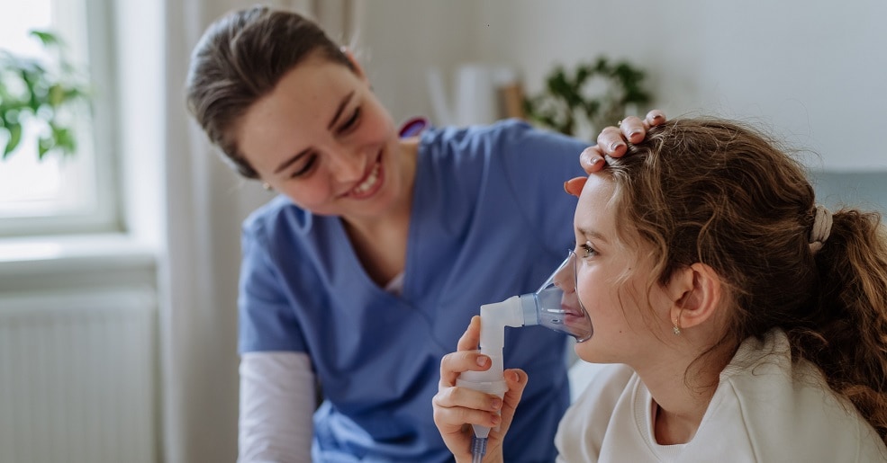 Little girl with inhaler in hospital room, nurse chcecking her.