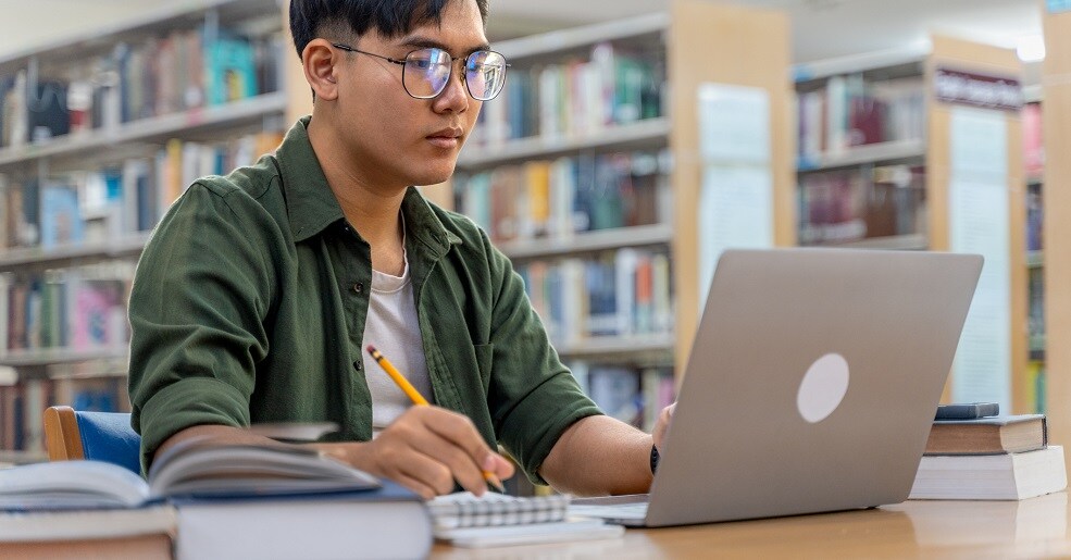 Student using laptop for study work at home.