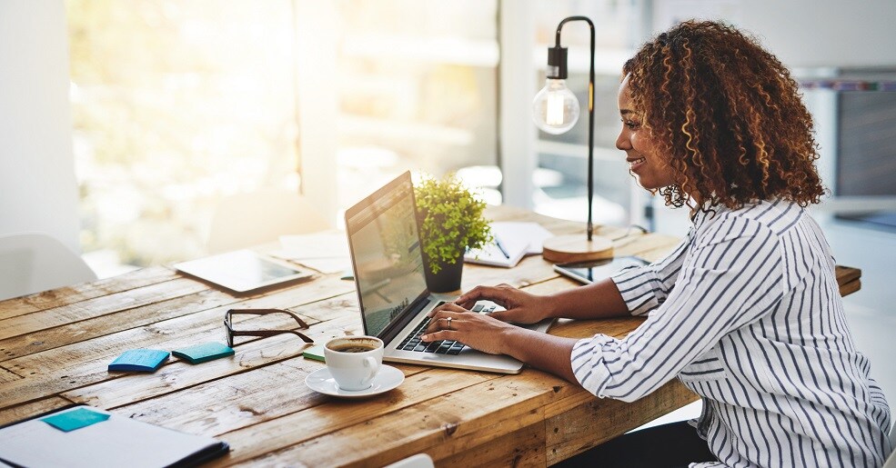 Woman working on laptop as home desk.