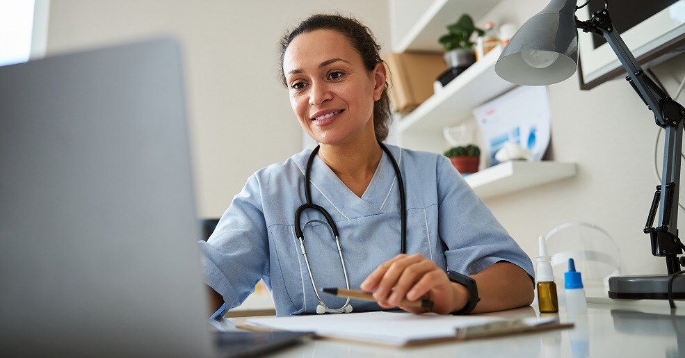 A doctor at her desk utilizing her laptop.