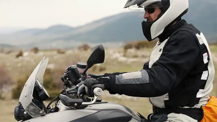 Man on white motorcycle with helmet and padding