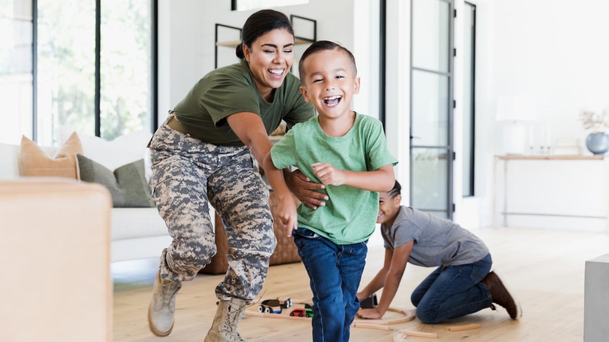A woman in uniform chasing her son around their home.