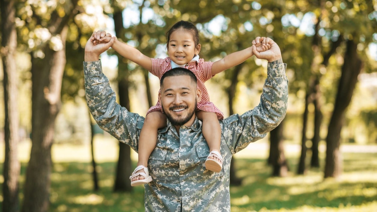 Man in military uniform with his daughter on his shoulders