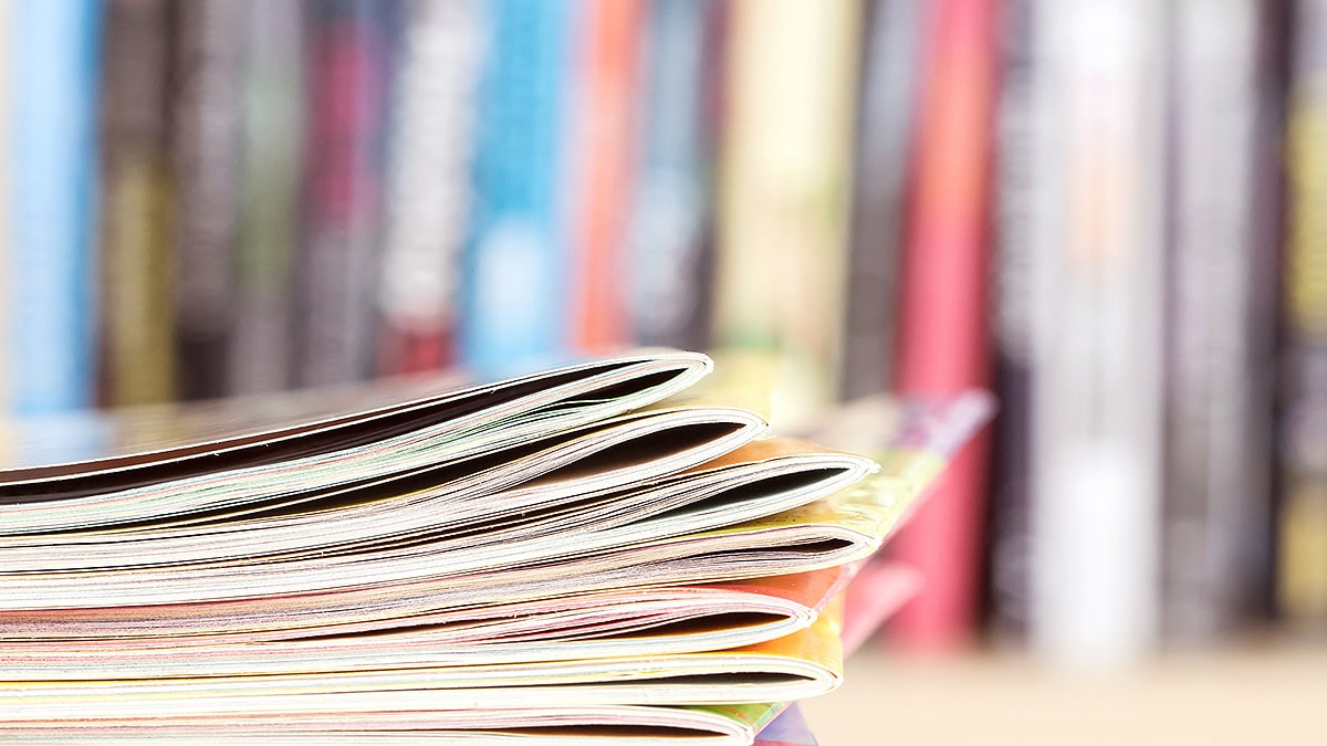 Stack of publications in front of a neat row of more books and publications.