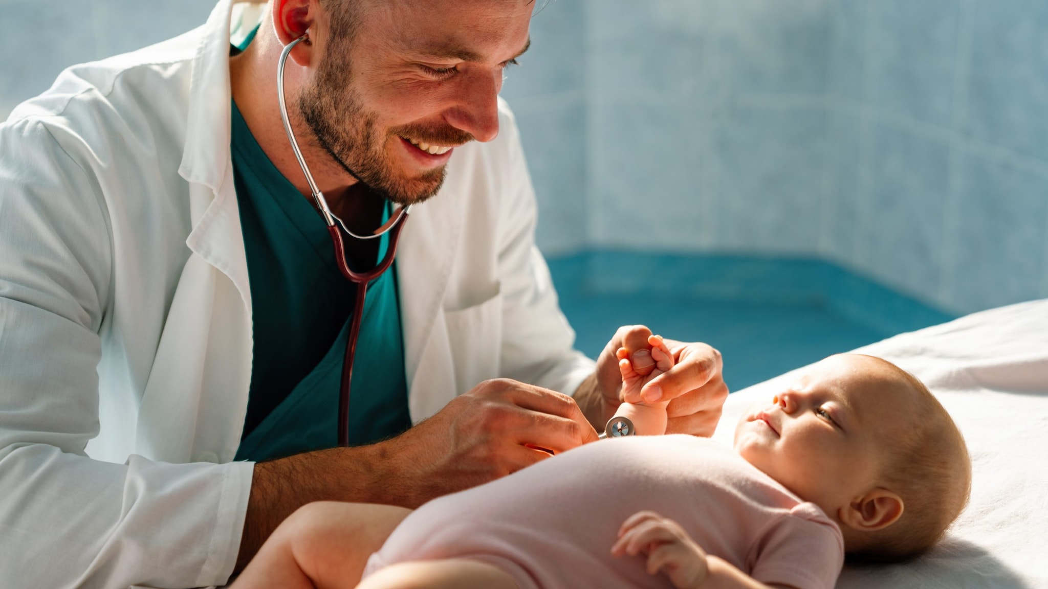 Doctor wearing stethoscope to exam baby during a check-up.