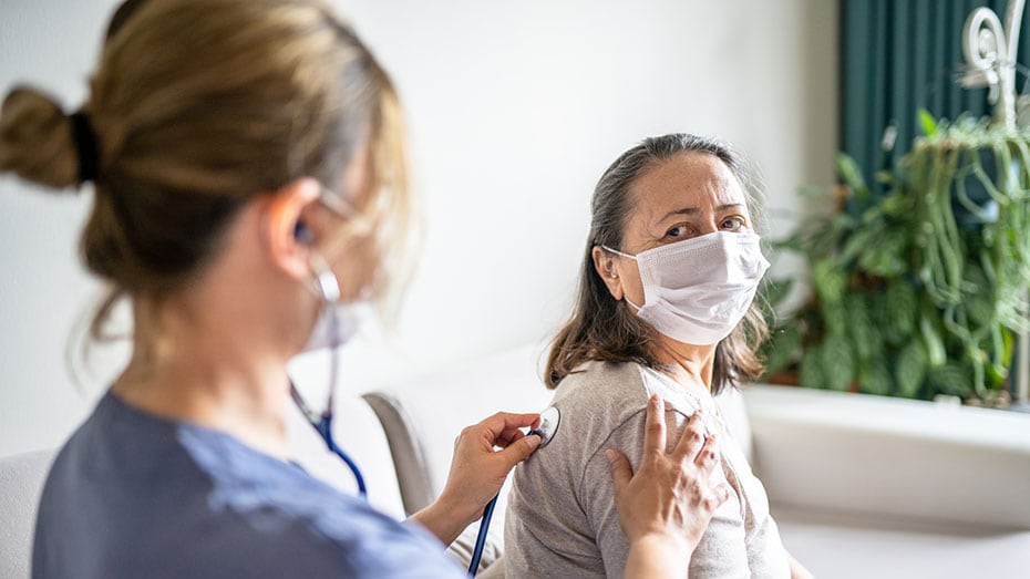 Una trabajadora de la salud escucha los pulmones de una paciente.