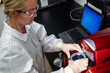 Female scientist working in a lab wearing protective glasses.