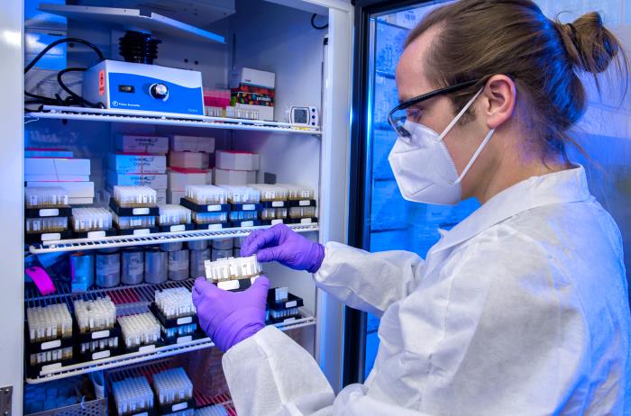 Laboratory inventory female lab tech wearing PPE holding sample.