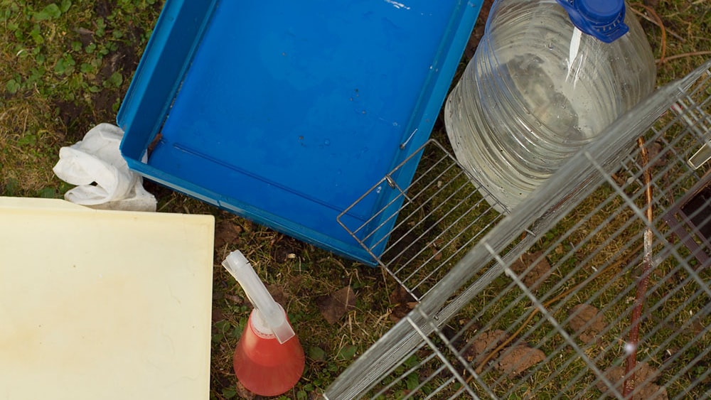 Overhead shot of a pet cage parts on the ground separated for cleaning.